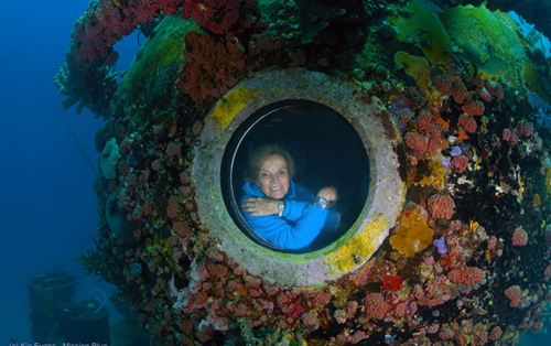 Dr. Sylvia Earle, "Her Deepness” peering out from a porthole.: Feature Photograph by Kip Evans / Mission Blue